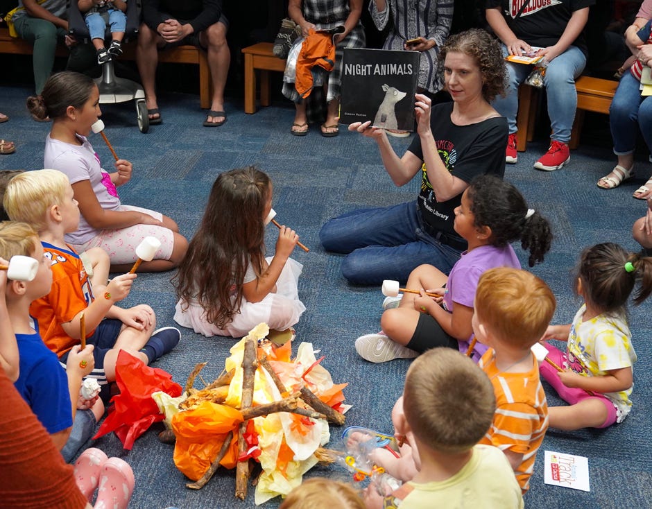 Youth Librarian Heather Nitzel reads a book to young patrons around a “campfire” over which the kids pretended to roast marshmallows skewered on a pretzel stick Sept. 17 at the Crestview Public Library.