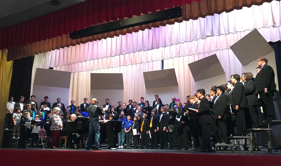 Ruckel Middle School chorus director Christian Feazell directs the massed Men’s Day Chorus following a day of workshops and singing for school choruses from throughout Okaloosa County. The event was Nov. 18 at Crestview High School.