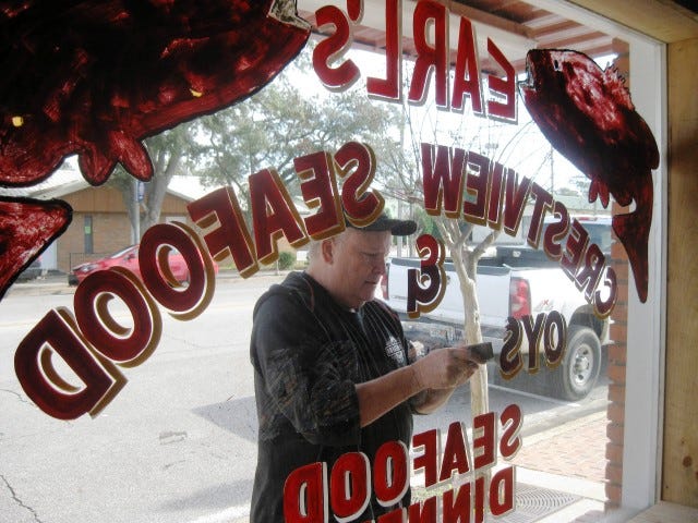 Hub City Barbecue and Grill owner Mike Carroll scrapes 13-year-old painted graphics from the former Earl’s Seafood on Main Street as he renovates the restaurant into his flagship eatery.