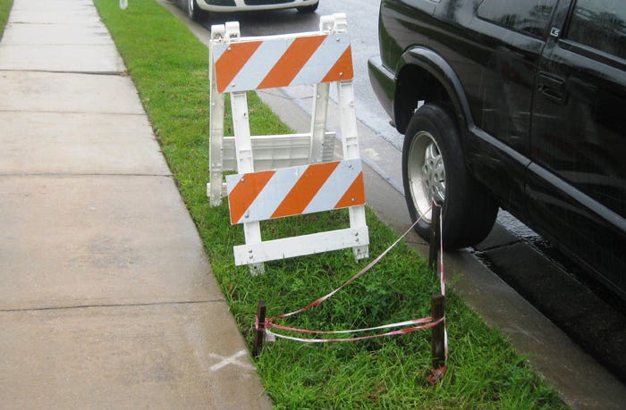 In the Fox Valley subdivision, a sinkhole has appeared alongside Swift Fox Run, caused by failing fiber-reinforced stormwater drainage pipe failures, which are also undermining the sidewalk, causing it to slope.