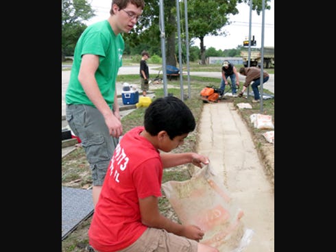 Eagle Scout candidate Tayler Vest, left, supervises Boy Scout Jonathan Bartosik during the walkway’s installation at the Crestview AMVETS post service flag array.