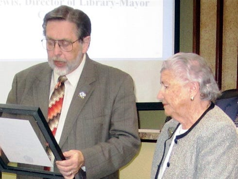 Mayor David Cadle reads to Joyce Mathis a resolution expressing appreciation for the public service of her late husband, former Mayor Ted Mathis.