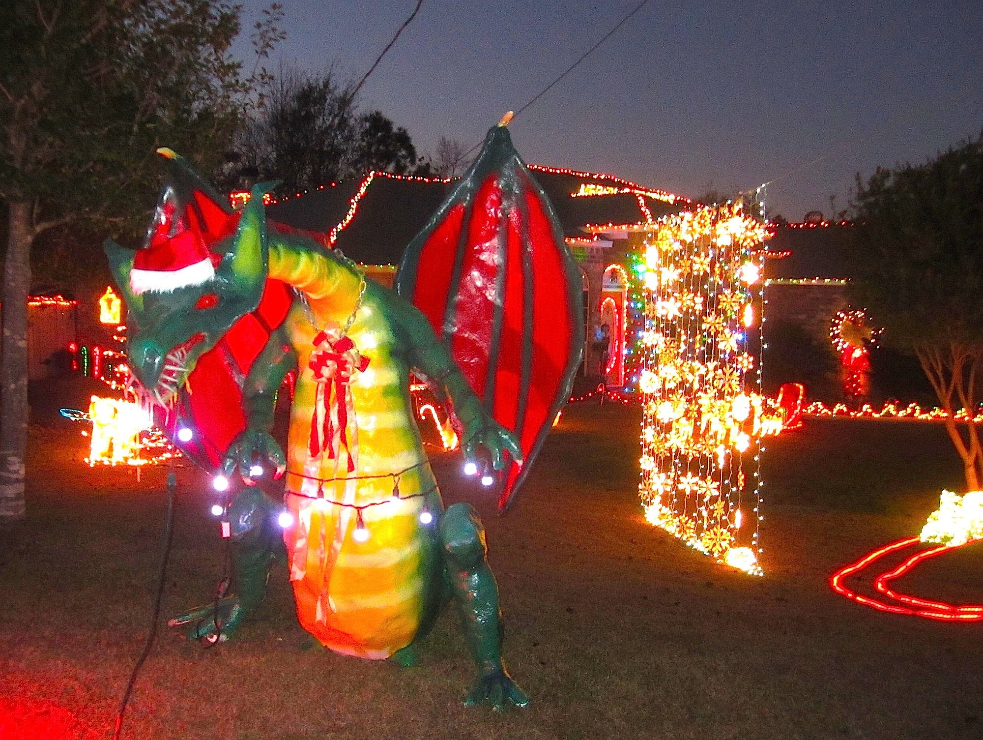 The Nicholses use red lighting, a Santa hat and a bow to transform their Halloween dragon into a festive holiday beast.