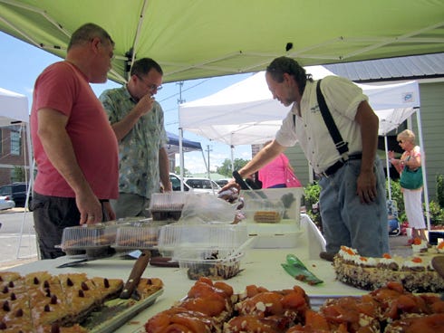 Shoppers eye assorted breads and pastries, including baklava and apricot tart, at Crestview’s downtown Farmers Market.