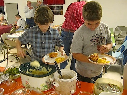 Buddies Thomas Kitchens, left, and Jacob Parker load their plates during their first pass through the line at last year’s Laurel Hill Harvest Supper. This year’s feast will be 6:30 p.m. Nov. 14.