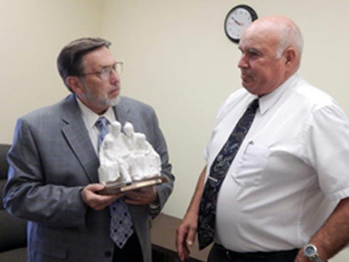 Mel Miller, outgoing president of the Fort Walton Beach Stake of The Church of Jesus Christ of Latter-day Saints' presents Crestview Mayor David Cadle with a porcelain figurine. Stake members honored Cadle's service to the city during a surprise June 5 ceremony.