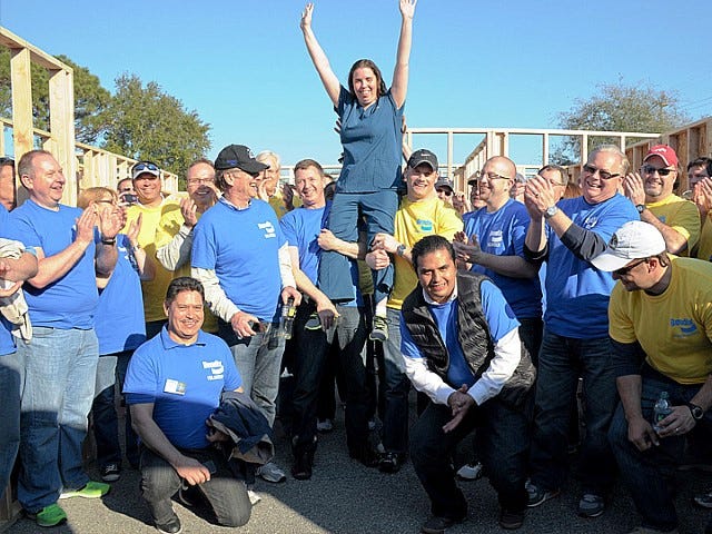 Crestview resident Jamie Peoples is held aloft by some of the 140 volunteers from Bendix Commercial Vehicle Systems who helped build her new Habitat for Humanity home's framework.