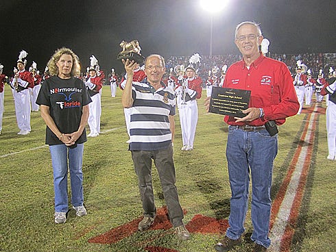 René Relandeau, center, Noirmoutier Sister City Committee president, hoists a Crestview High Bulldog during an exchange of gifts with Principal Bob Jones Friday night. Crestview High French teacher Chris Lanoue, left, translated during the presentations.