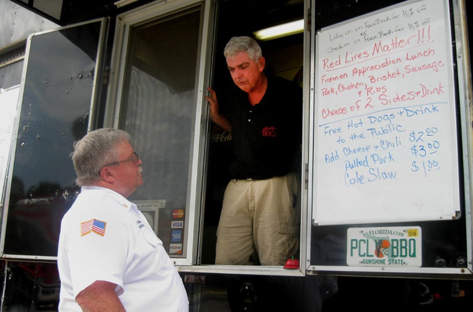 Assistant Crestview Fire Chief Ralph Everage examines selections available on the menu board at Buddy's BBQ. Owner Naaman Eicher presented Red Lives Matter lunch for firefighters on July 29.