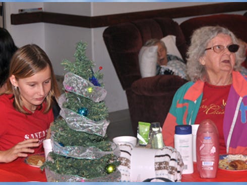 Railey Conner, 12, left, enjoys snacks with her great-grandmother, Roxy Buchanan, 84, at a Christmas party at Carrington Manor on Christmas Eve. Railey and her family gave gift bags to Buchanan and other residents during the party.