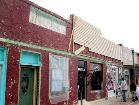 A crack above the green door was discovered on this 1920s Main Street building’s façade when vinyl siding was removed.