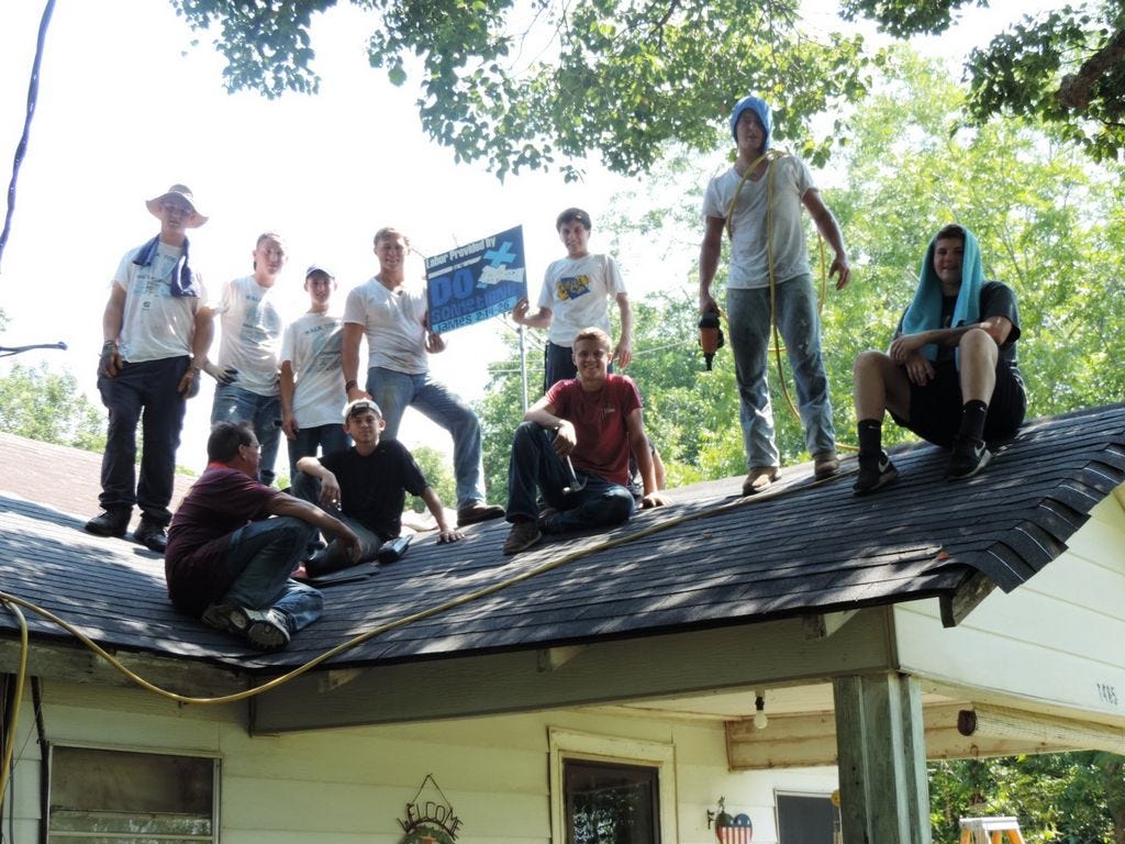 A Pilgrim Rest Baptist Church crew poses atop a house where they are replacing roof shingles during “Do Something” summer camp.