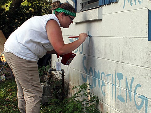 Natalie Mize, 14, tags the front of a Baker house with the hashtag #DoSomething and her seven teammates’ names before covering it with a fresh coat of paint.
