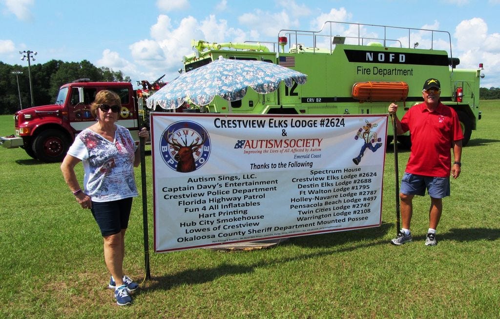 Crestview Elks Jean and Bob Daniel flank the sponsors banner on June 11 during the Exceptional Children's Day at Elks Park off Fairchild Road.