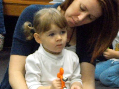 Katie Mitchell, 1, left, and Jamie, her mother, listen during the Crestview Public Library’s Lap Sit.