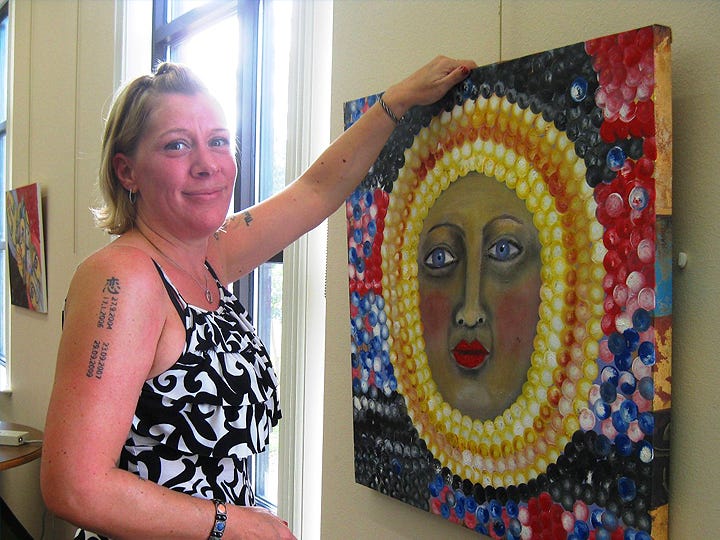 Crestview artist Nicole Weaver hangs one of her colorful abstracts on the Crestview Public Library's exhibition wall.