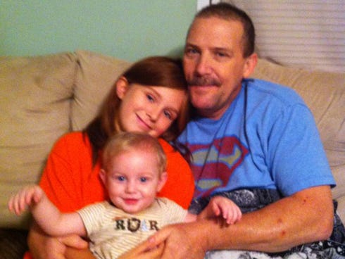 Bruce Akers embraces his grandchildren Jazmine, 10, and J.T., 1, for a family photo. Family members seek the community's support in raising funds for Bruce, who will soon receive chemotherapy for bladder cancer.