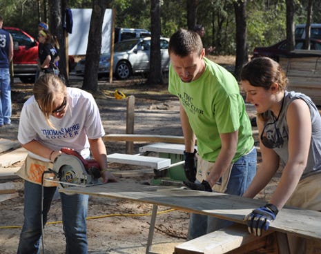 Chelsea Dietz, Dan Pherman and Maggie Waller, Habitat for Humanity volunteers from Thomas More College in Kentucky, saw boards for a Lee Avenue home on Monday in Crestview.