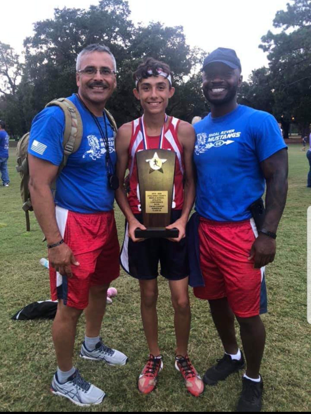 Alex Buena (middle) poses with his coaches, Enrique Torres (left) and Fernando Faust (right) after placing first in the county championship meet.