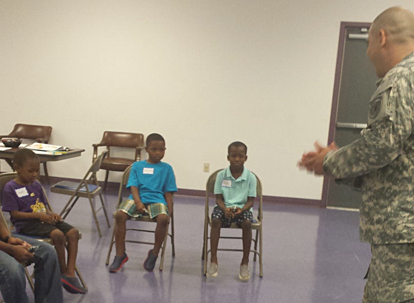 United States Army Sgt. Timothy L. Pickard speaks to David Cornell, 5; LaRon Jolly, 6; and LaRonta Jolly, 7, during Crestview's Summer Reading class at Mount Zion AME Church.