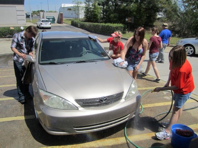 From left, Crestview High School chorus members Johnathan Berry, Morgan Seip and Anisia Jordan dry a patron's car as chorus mom Tera Wilson rinses off suds.