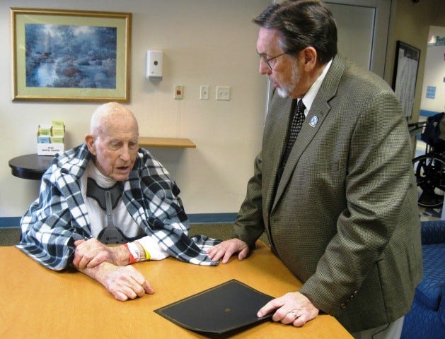 Mayor David Cadle converses with John McMahon before issuing a proclamation saluting the retired forester on his 90th birthday.