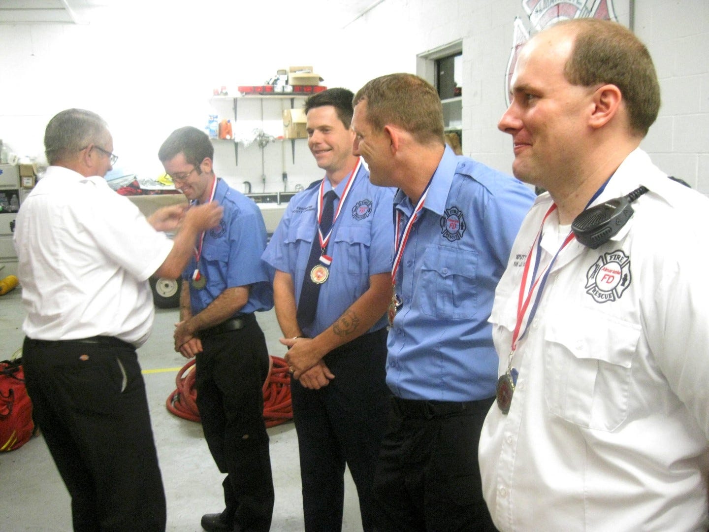 Almarante Volunteer Dire Department Chief Charles Carroll hangs one of the first Chief’s Recognition Award medals around the neck of firefighter Sean Epperson, who, with firefighters Scott Zamorski and Randle Henderson and Deputy Chief Ryan Jaycocks were recognized for rescuing three dogs from an August house fire. (BRIAN HUGHES | News Bulletin)