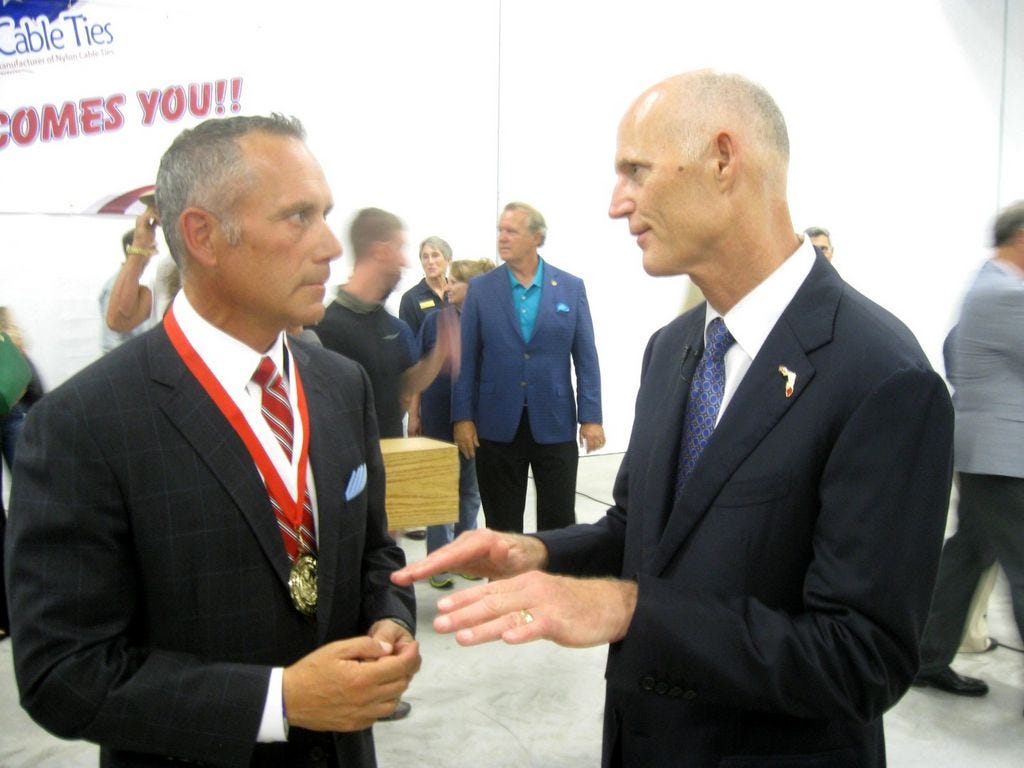 Bay State Cable Ties president and owner Bob Sires discusses his company's expansion with Gov. Rick Scott on Thursday. Sires is wearing the governor's business ambassador medal, which Scott presented during his visit to the Crestview plant.