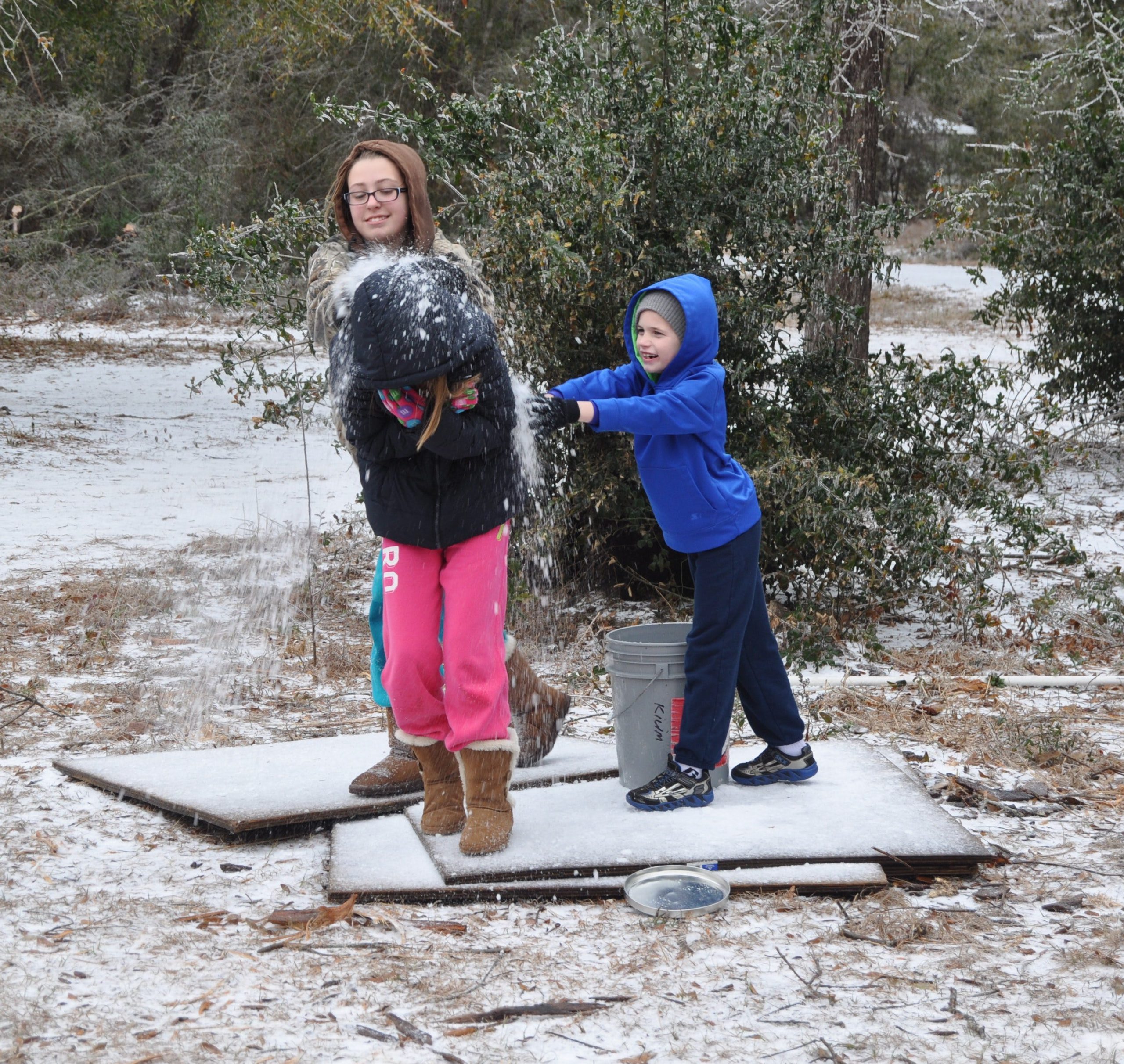 From the left, 13-year-old Ashlyn Broxson tosses ice at her 10-year-old sister Abby with the help of their cousin Landon Broxson, 8, at their Holt residence on Wednesday.