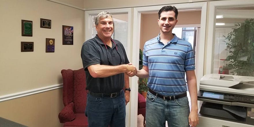 Crestview News Bulletin Editor Thomas Boni, right, shakes hands with Brian Hughes before he leaves the CNB office for a final time as reporter. (DAWN BARNES | News Bulletin)