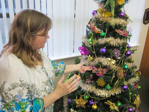Library clerk Audrey Milcarek adjusts decorations on this Mardi Gras tree.