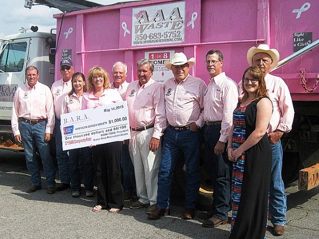 Making Strides Against Breast Cancer’s Donna Fought, holding check, and Kyla Pugh, right front, accept a $1,000 donation from Baker Pro Rodeo organizers Mark Stalnaker, Ernie Brewbaker, Edith Elder, Russell Moorman, Joe Fisher, Bill Graham, President Mark Todd and Jim Silcox.