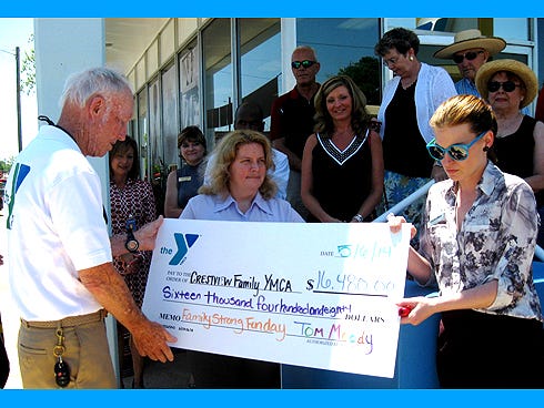 YMCA Executive Director Tom Moody presents a check — including funds raised during the Family Strong Fun Day held at his Old Warrior Ranch — to YMCA board member Casey Dean.