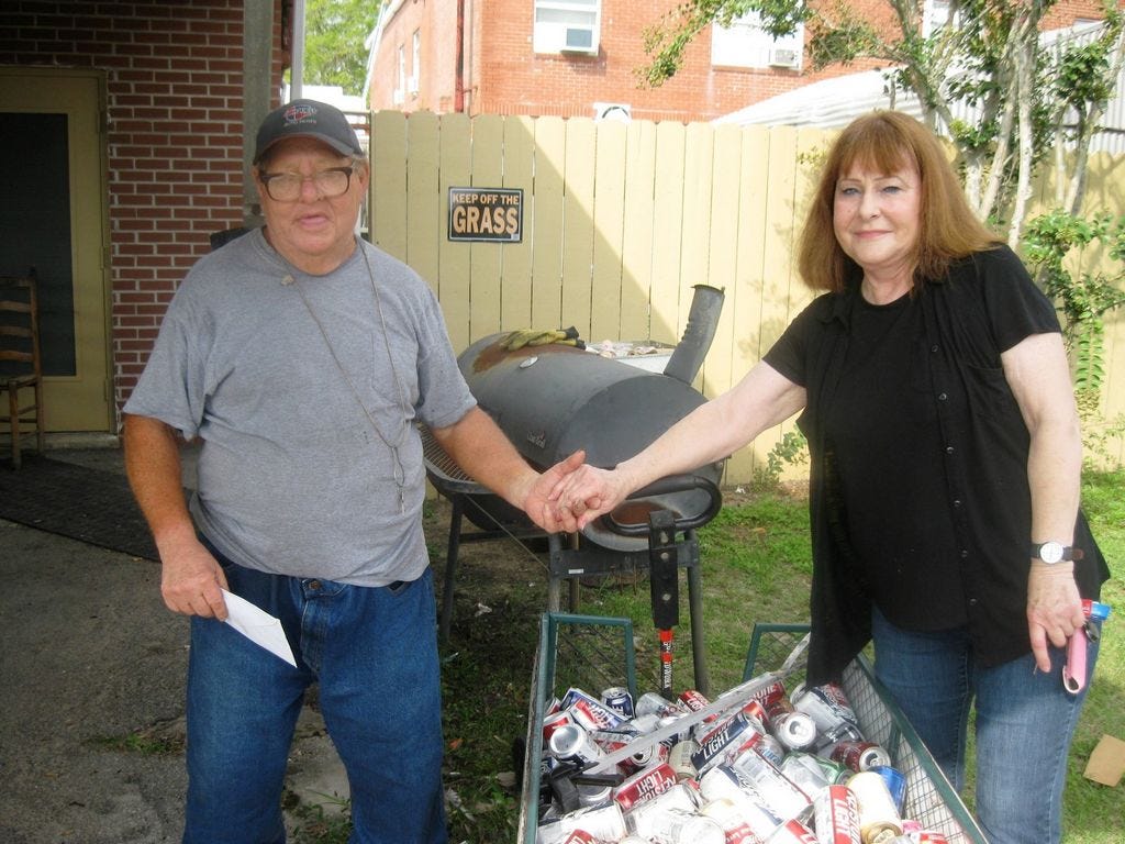 Friendly Florist owner Susan Hollingshead grasps Elvit Enlow's hand after presenting him with more than $1,100 from donors who were moved when they learned thieves stole his hard-earned aluminum cans.