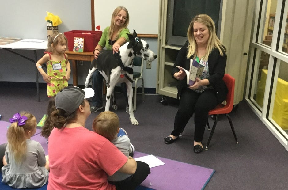 Area residents and Dozer the dog listen as Dr. Chelsea Evans of Okaloosa Eye Care reads "Dogs Don't Need Glasses" by Adrienne Geoghegan recently at the Crestview Public Library. [Special to the News Bulletin]