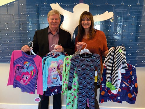 Pictured, from left: Ken Hair, Children in Crisis president & CEO, receives a donation of pajamas from Lisa and the Pajama Patrol from Coast 93.3's "Logan & Logan Morning Show." The pajamas, which benefited at-risk foster children living at the Children in Crisis Neighborhood, will keep the kids warm during the winter.