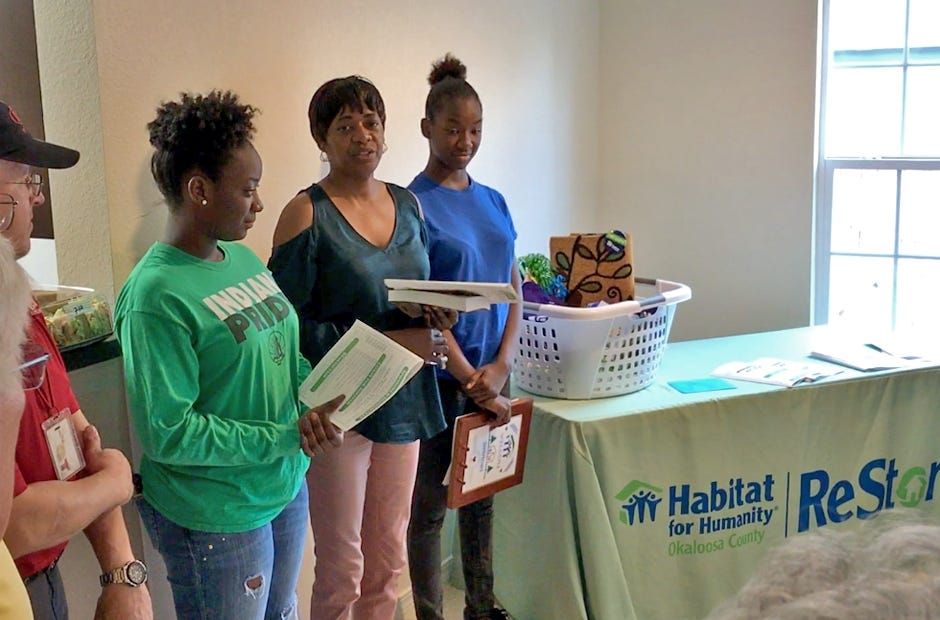 Esther Simmons (center) and her daughters Mirria (left) and Elesi (right) thank volunteers from Habitat for Humanity as they are presented the keys to their new home. [MARK JUDSON/NEWS BULLETIN]