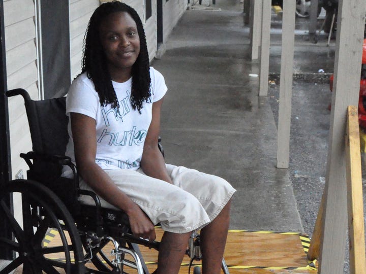 Britainy Pate, 27, sits in her wheelchair on a wooden ramp that Newlin Carter, her father, built after her family moved into their apartment.