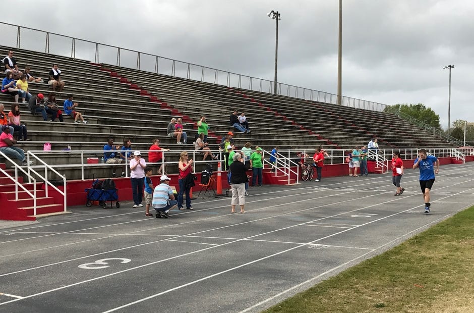 Harrison Mauldin (far right) completes one of 25 laps around the track during his 10-kilometer competition as fans cheer him on. [MARK JUDSON/NEWS BULLETIN]