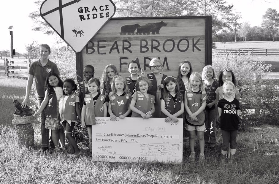 Crestview Girl Scout Troop 676 presented a check for $550 to Sherry Hall of Grace Rides (back row, left) April 10 in DeFuniak Springs. Troop members, from left, are Alexa Tangonan, Shyteria Cowart, Christy Brethauer, Kimmie Raiche, Cinzia Cadenhead, Kaylyn Converse, Miley Milani, Julianna Thornton, Ainsley Gardner, Temperance Brindle, Myla Gardner, Elliana Gallegos, Julianne Thornton and Brooklynn Barber. [Special to the News Bulletin]