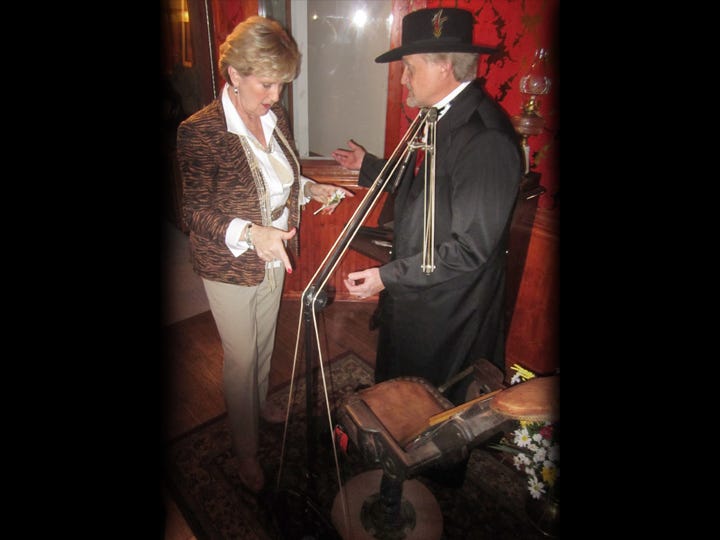 Dr. Richard Thomas, garbed as a Wild West gambler, gives Edie Giovanini a tour of his lobby exhibit room displaying artifacts of Dr. John "Doc" Holliday, including his dental chair.