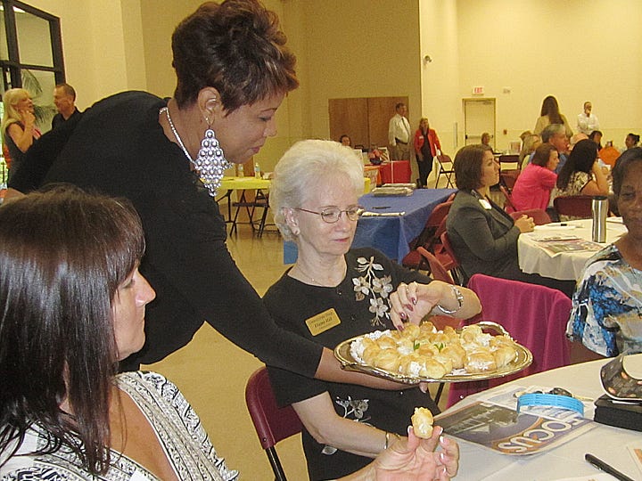 During the October chamber of commerce breakfast, volunteer Alicia Booker serves Elaine Hill an hors d'oeuvre typical of the Wine Gala's gourmet fare as chamber board member Alison Broxson observes.