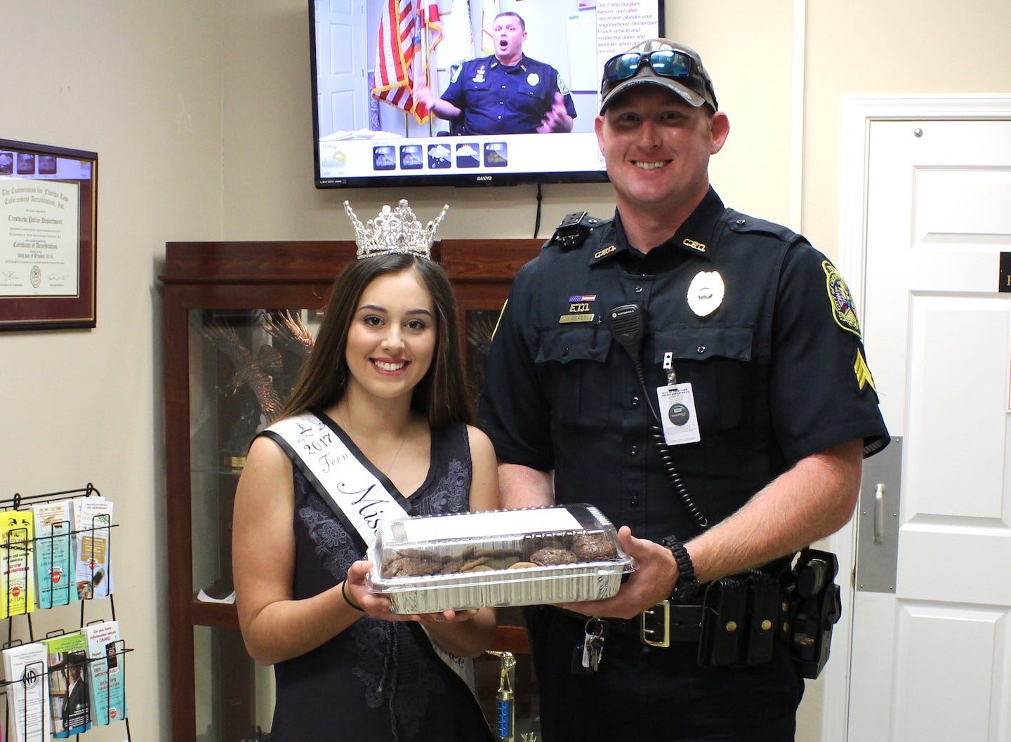 Crestview student Lindsay Huckabee, Teen Miss Choctawhatchee Northwest Florida, presents a container of home-baked treats to Crestview Police Sgt. Josh Grace as a “thank you” during the recent National Police Week. [BRIAN HUGHES | Crestview Police Department]