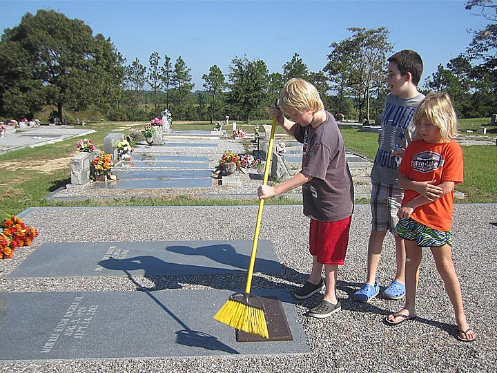 Neal Twitty, 9, his sister Hannah, 7, and their cousin Bryce Wooten, center, 11, clean up the grave of their grandfather and great-grandfather, respectively, at Almarante Cemetery during last year's cleanup.