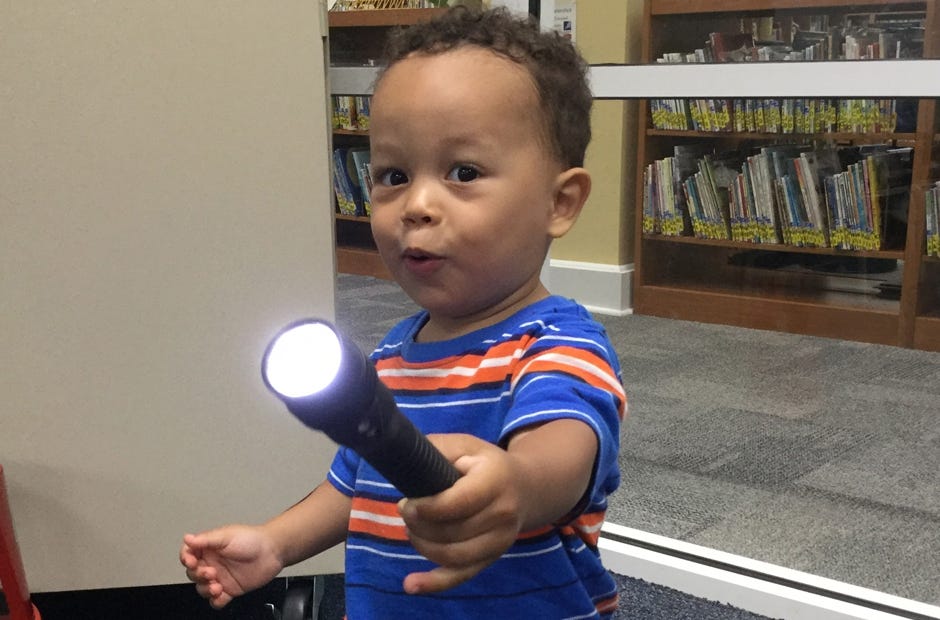 Jayce Redding, 2, of Crestview, said "Woah!" as he played with Crestview Police Department Officer Wanda Hulion's flashlight during the age 0-2 class recently at the Crestview Public Library. [Special to the News Bulletin]