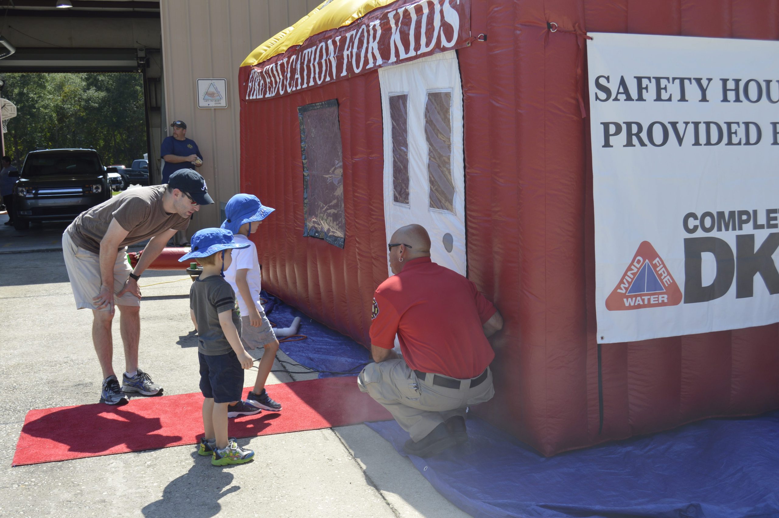 Firefighter Alan Clifton shows two young Crestview residents through the smoke safety house. [ALICIA ADAMS | News Bulletin]