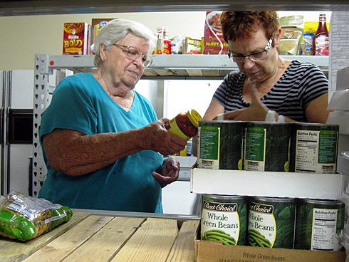 Volunteers Brigitte Innis and her niece, Elli Pfeiffer, fill bags with food for a Sharing and Caring client family.