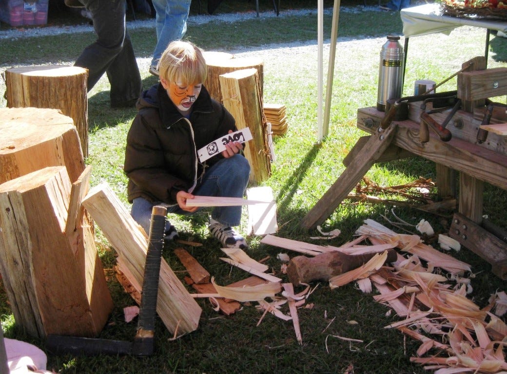 Josiah Maulden, 9, selects a souvenir piece of cypress from shingle-making scraps at the Baker Heritage Festival.