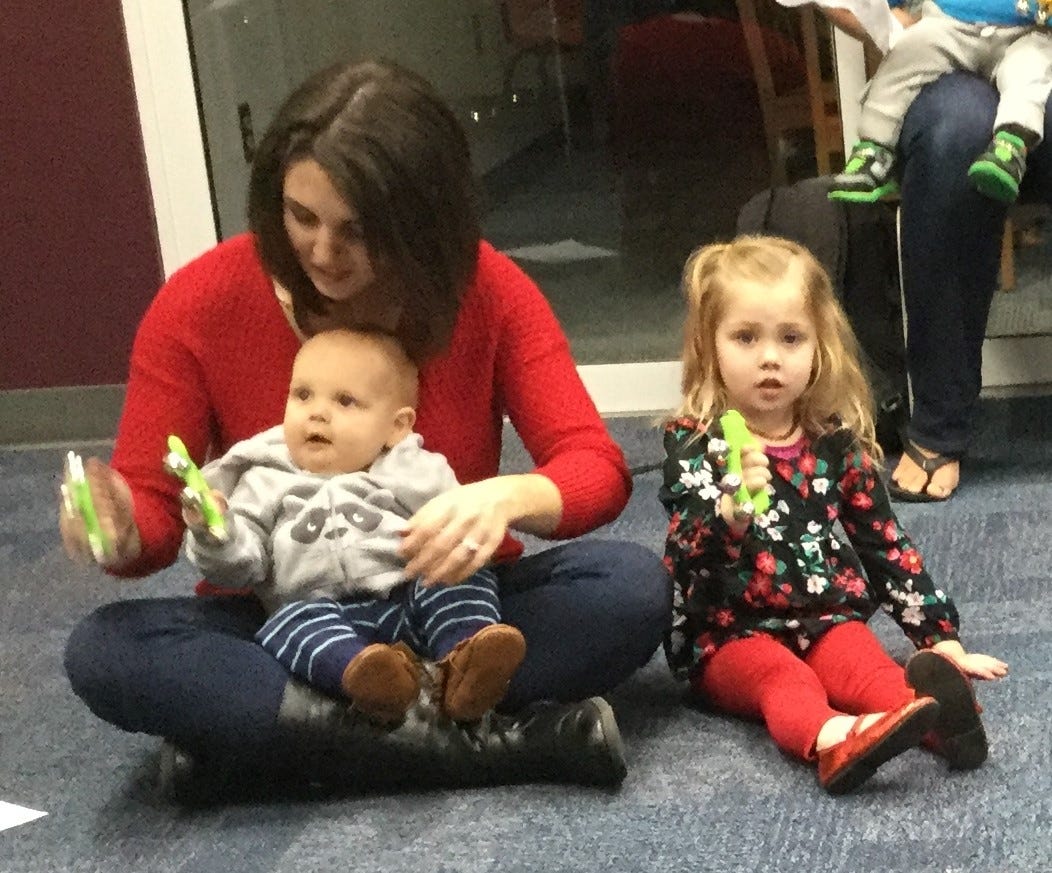 Tiffany, Hayden (9 months) and Everly (2) Jennings jingle bells during Library Class on Friday, Dec. 15. They are Crestview residents. [Special to the News Bulletin]