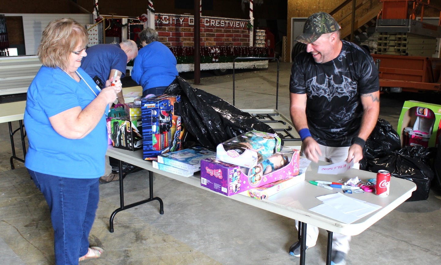 Crestview Citizens Police Academy Alumni members Brenda Cadenhead and Eric Marshall share a laugh as they sort Cops For Kids toys and strike out barcodes on each package Dec. 19. [BRIAN HUGHES | Crestview Police Department]